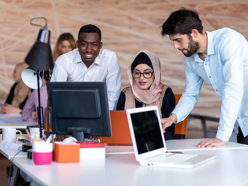 Three people around a desk using computers